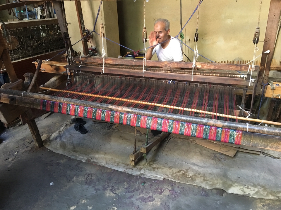 Un homme tissant sur un métier à tisser dans un atelier.