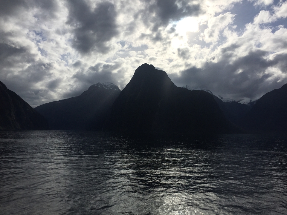Silhouette de montagnes autour d'une grande étendue d'eau sous un ciel nuageux.