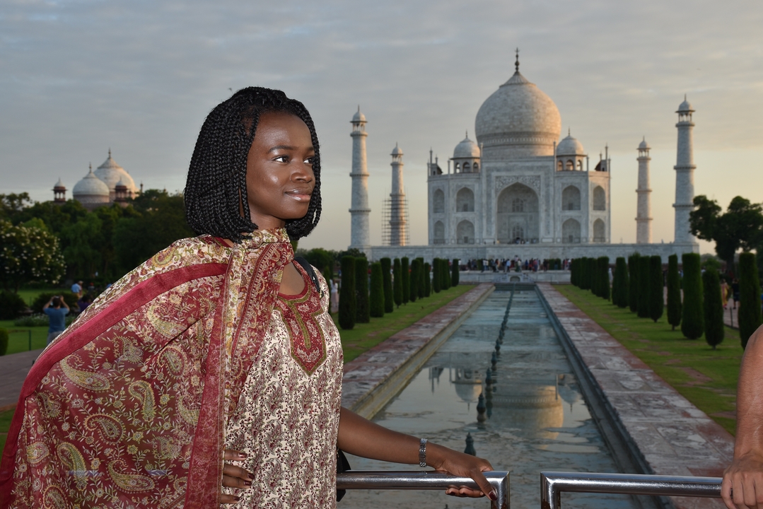 Une femme en tenue traditionnelle pose devant le Taj Mahal.