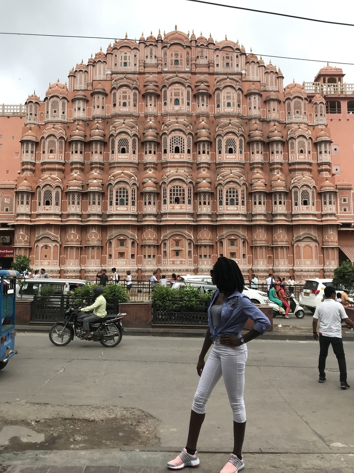 Une femme posant devant le Hawa Mahal dans un cadre de rue animée.