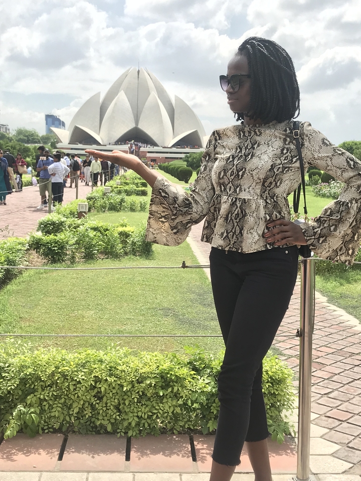 Une femme posant avec la paume ouverte devant un sentier de jardin rempli de touristes.