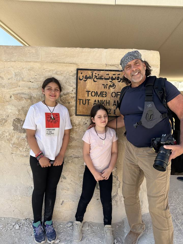 Man and children posing with a sign outside a tomb.