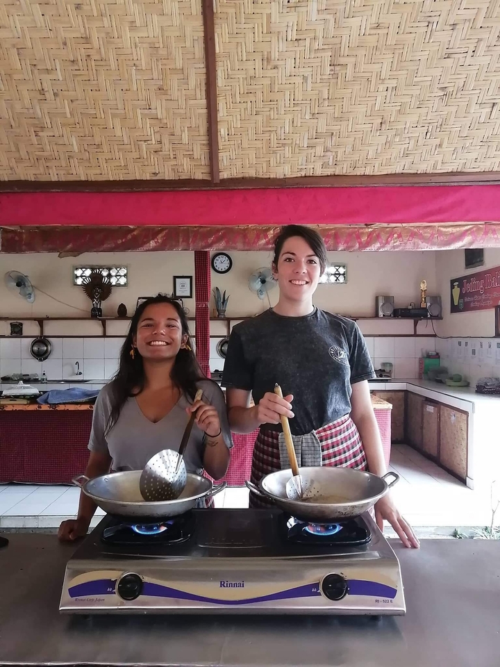 Two people smiling in a cooking class setting with cooking utensils.