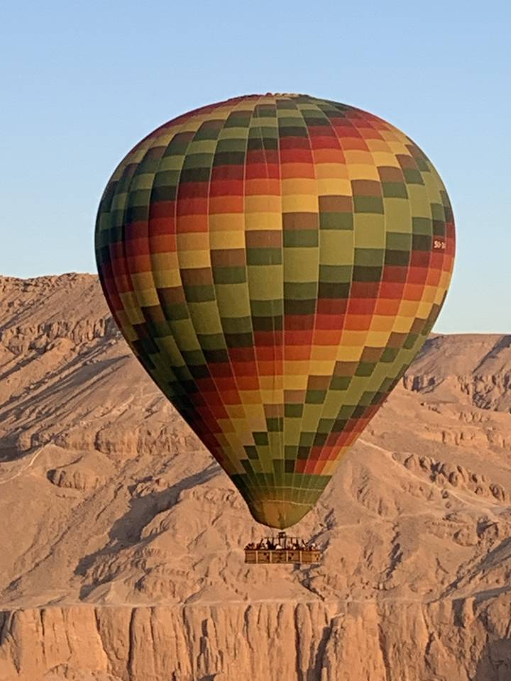 Hot air balloon flying over desert landscape.