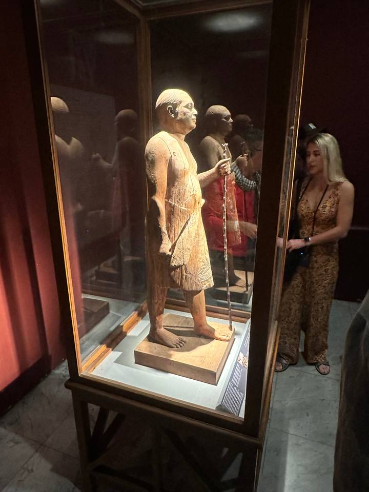 Vue de côté d'une statue en bois dans une vitrine.