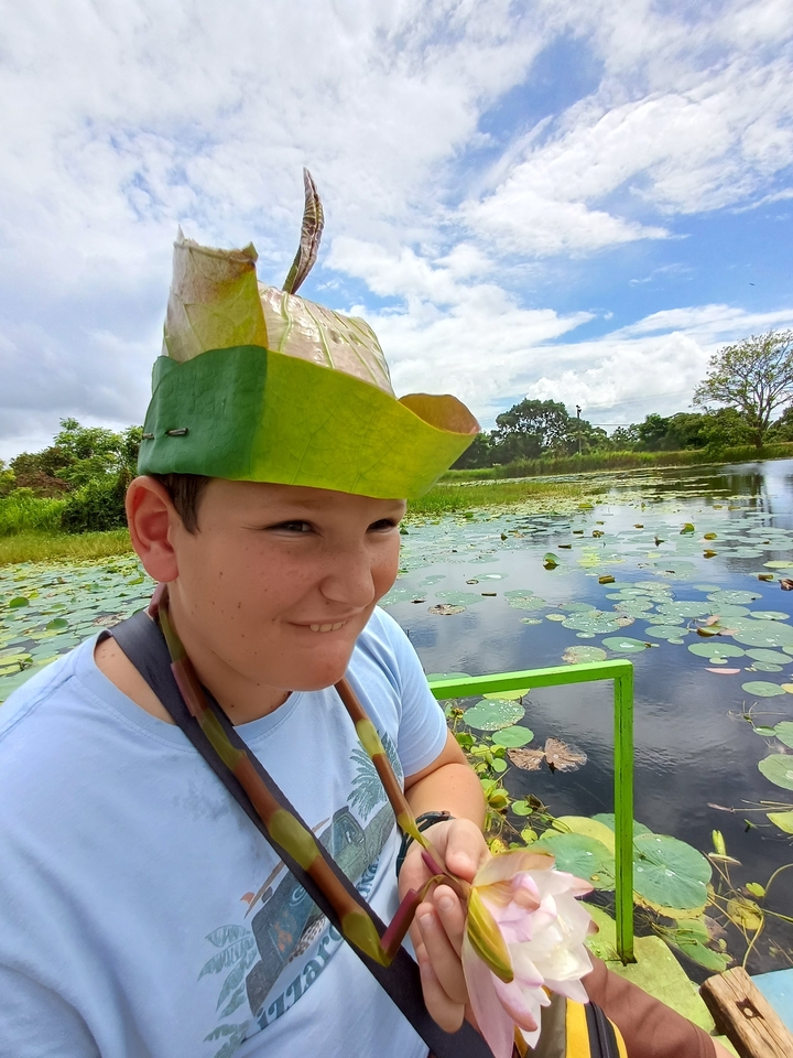 Garçon avec un chapeau de feuille dans un cadre aquatique luxuriant.