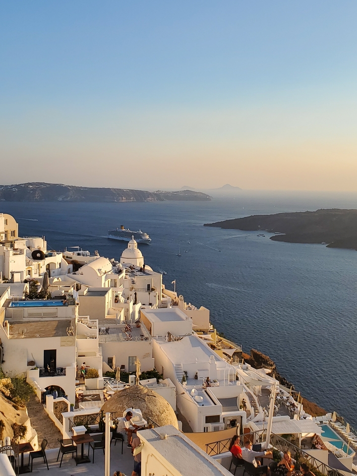 Vue d'un navire de croisière et de bâtiments blancs au bord de la mer au coucher du soleil.