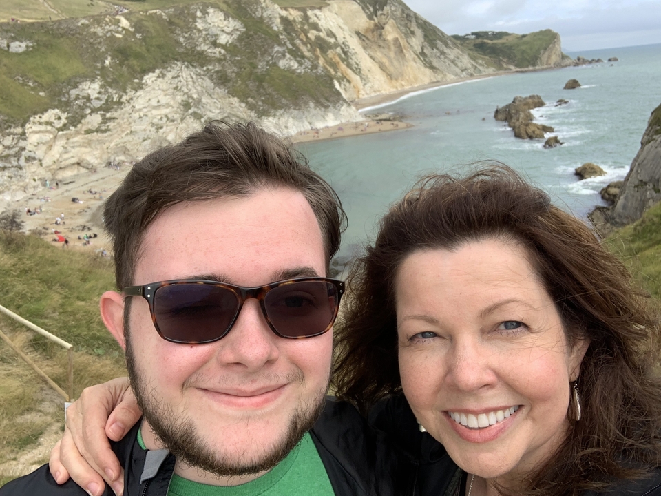 Un couple souriant à la caméra avec une vue côtière pittoresque.