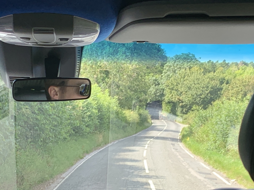 Vue floue depuis l'intérieur d'un véhicule montrant une route et des arbres.
