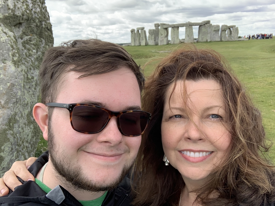 Deux personnes souriantes avec Stonehenge en arrière-plan.