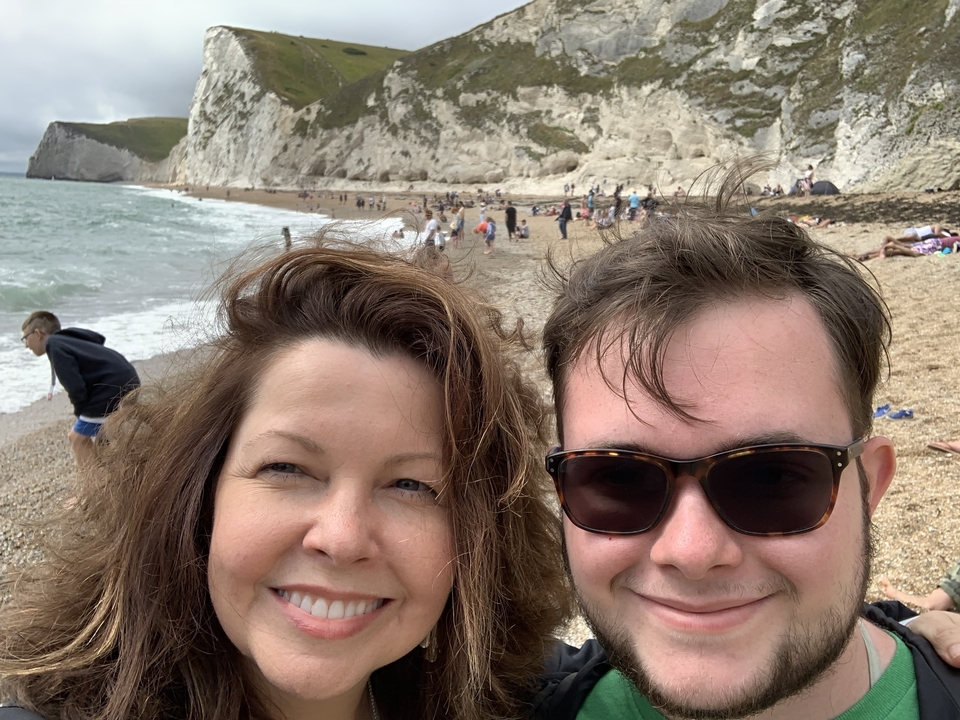 Couple sur une plage de galets avec des falaises en arrière-plan.