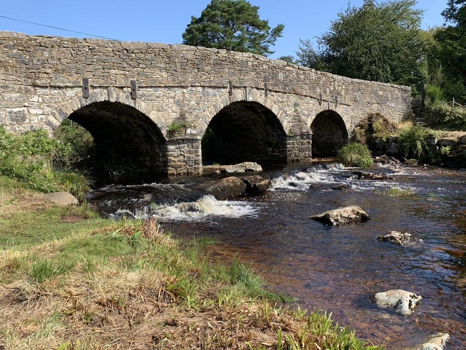 Pont historique en pierre au-dessus d'une rivière qui coule.