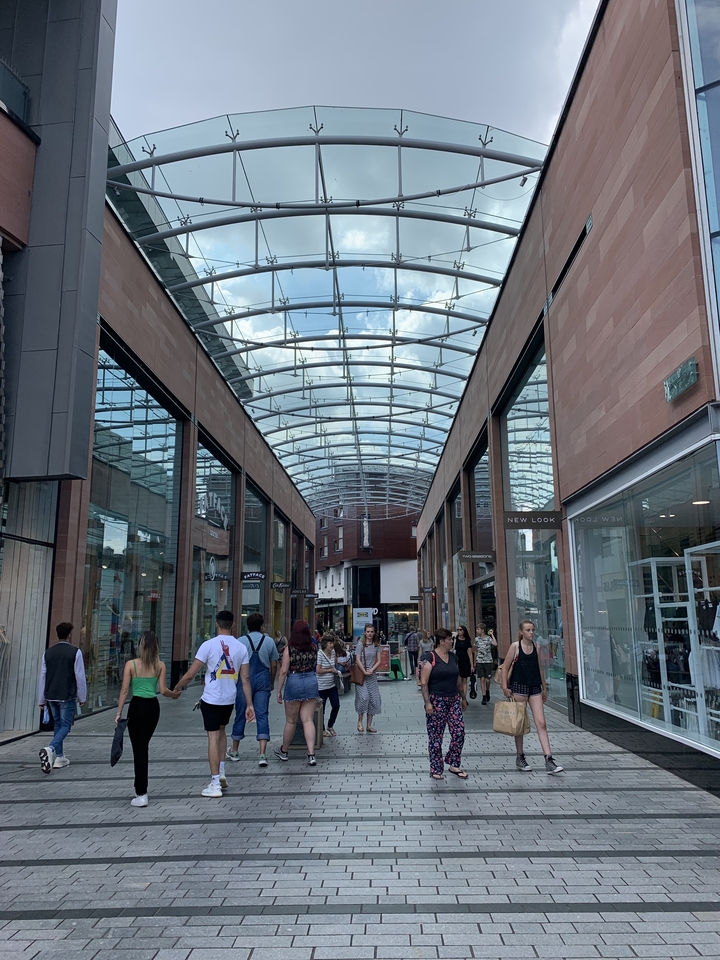 Centre commercial couvert de verre avec des gens qui marchent.