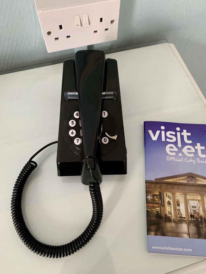 Téléphone rétro et un guide de la ville d'Exeter sur une table.