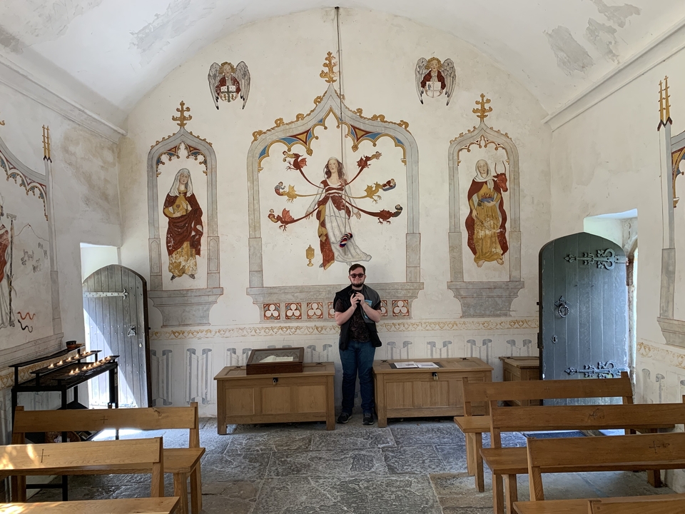 Personne debout à l'intérieur d'une chapelle historique avec des peintures murales.