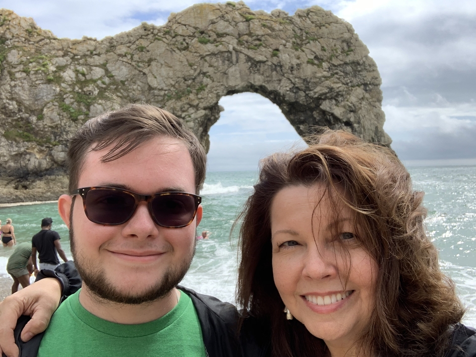 Un couple posant devant une arche rocheuse naturelle au bord de la mer.