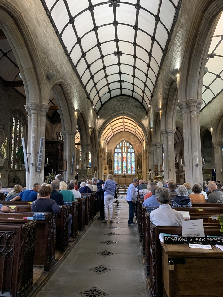 Groupe de personnes à l'intérieur d'une église historique avec des vitraux.