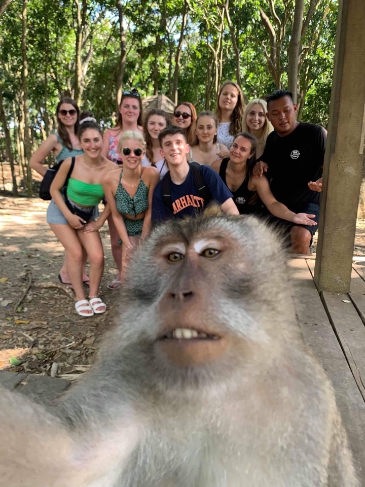 A group of people posing with a monkey in the foreground.