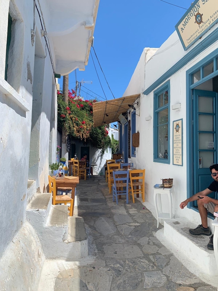 Un charmant café dans une ruelle étroite avec des chaises colorées.