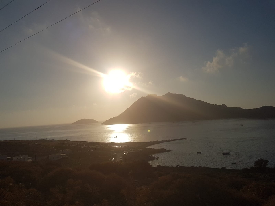 Un soleil couchant sur un paysage marin d'île montagneuse.