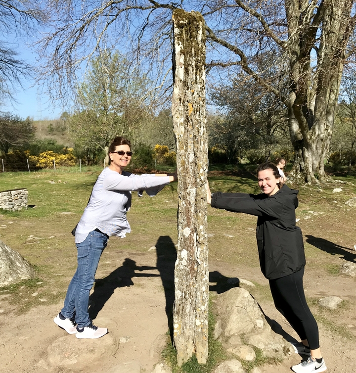 Deux personnes interagissant avec une grande pierre dans un cadre de parc.