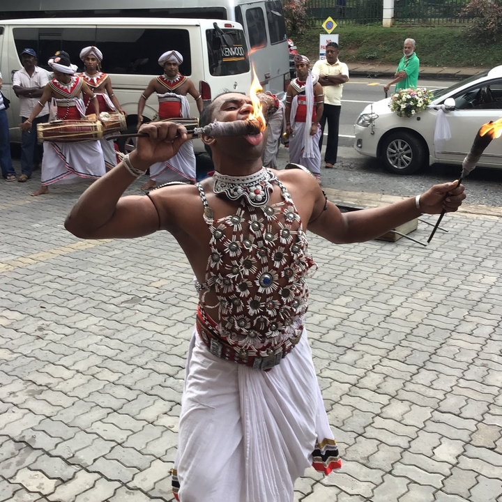 Homme exécutant un tour de cracheur de feu en tenue traditionnelle.