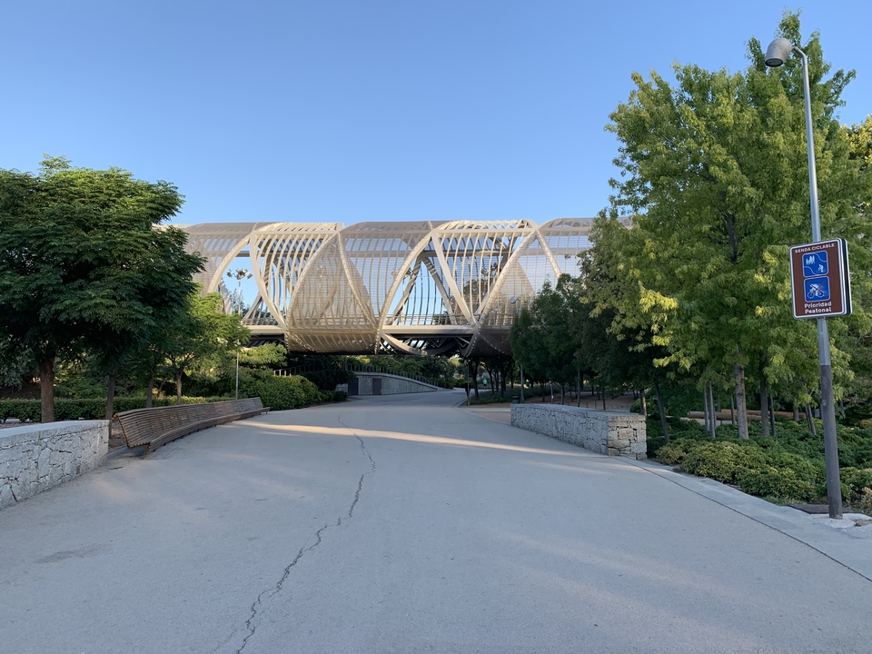 Structure de pont moderne dans un parc entourée d'arbres.