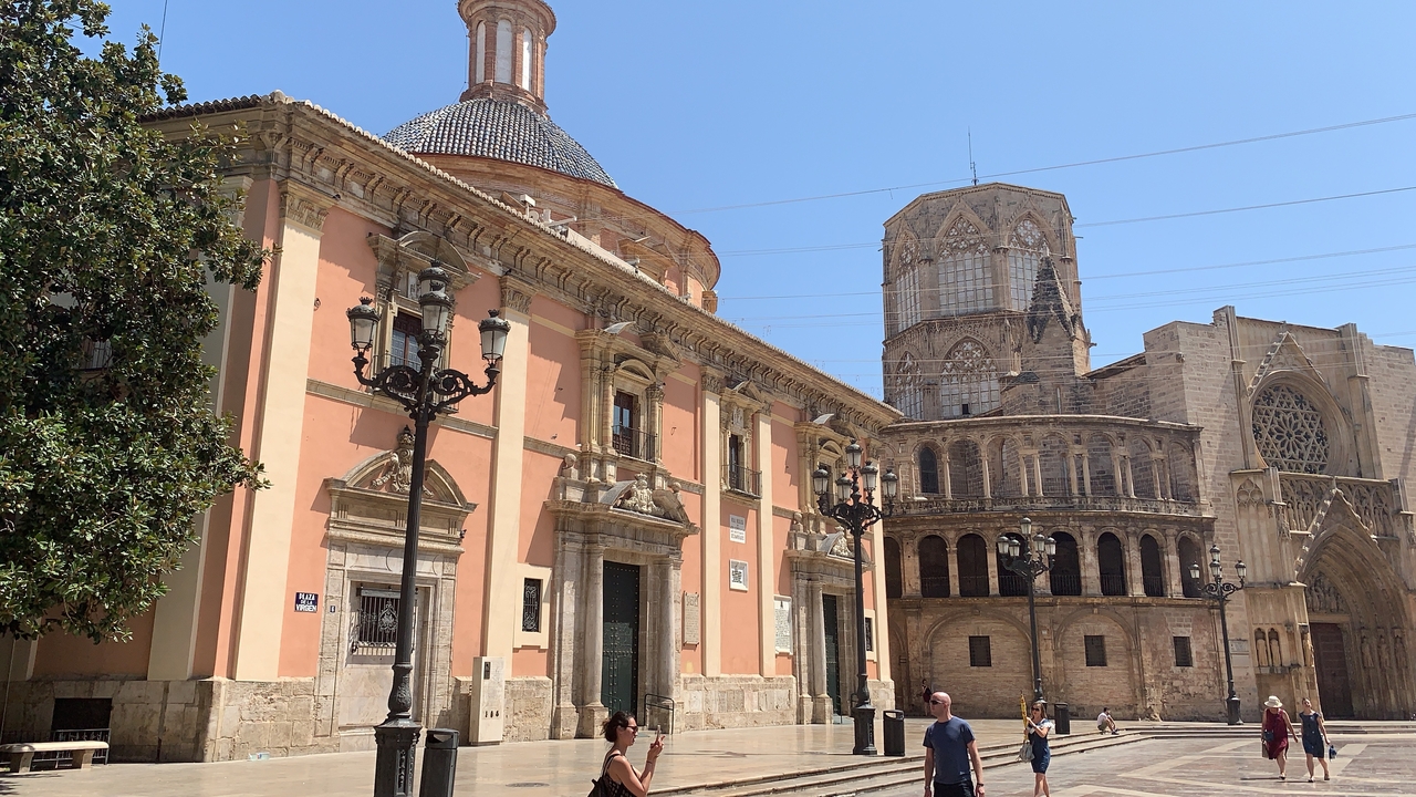 Bâtiment historique avec une grande cathédrale et une entrée ornée, des gens se promenant autour.