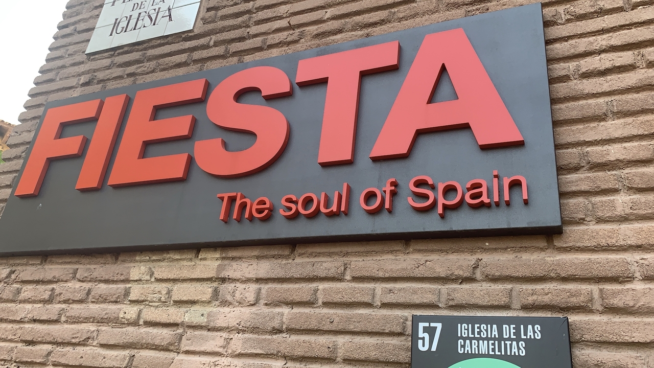 Panneau sur un mur de briques avec du texte en gras et un panneau directionnel plus petit en dessous.