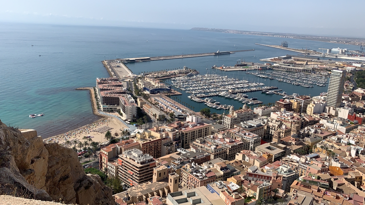 Vue aérienne d'une ville côtière avec un port de plaisance et une plage.