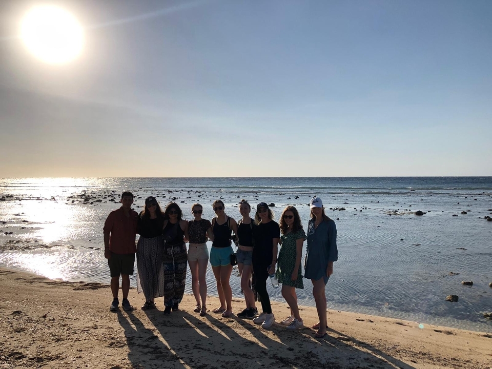 Groupe de personnes debout sur une plage au coucher du soleil.