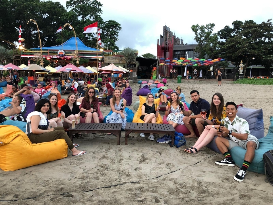 Un groupe de personnes assises sur des poufs colorés dans un lieu en bord de mer.