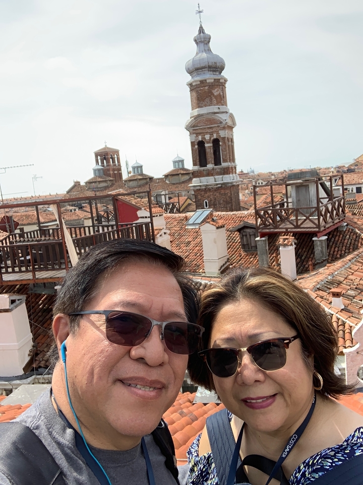 Deux personnes sur un toit avec une vue sur des bâtiments médiévaux.