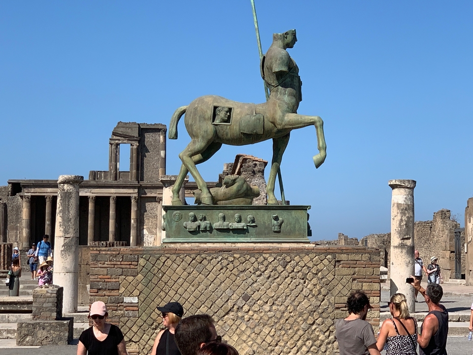 Sculpture d'un cheval et de personnes dans des ruines.