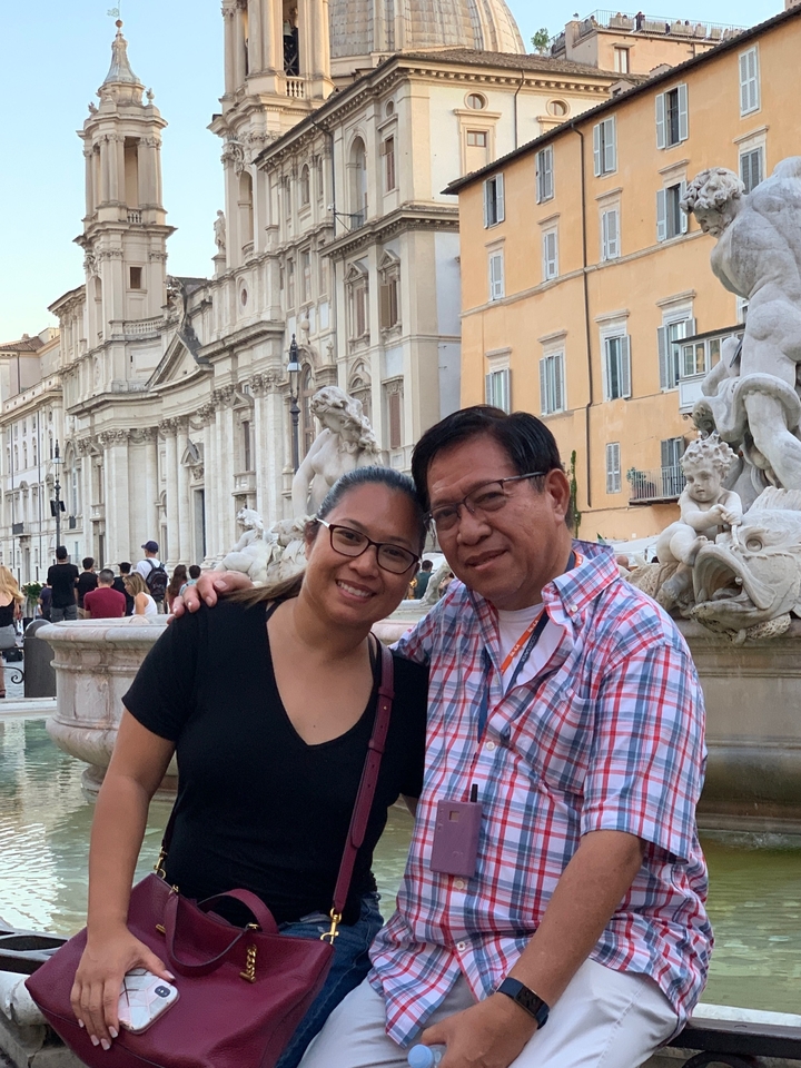Deux personnes près d'une fontaine historique sur une place.