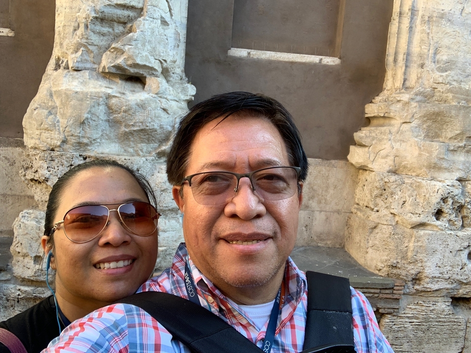 Deux personnes souriantes devant des murs de ruines antiques.