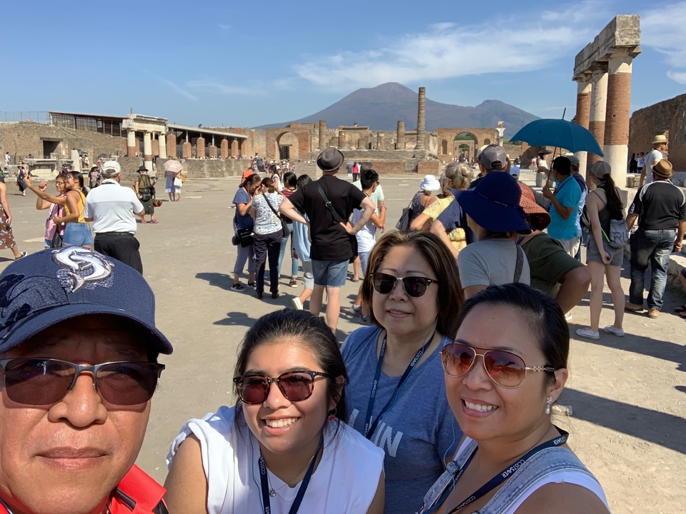 Groupe de personnes sur un site historique avec un volcan en arrière-plan.