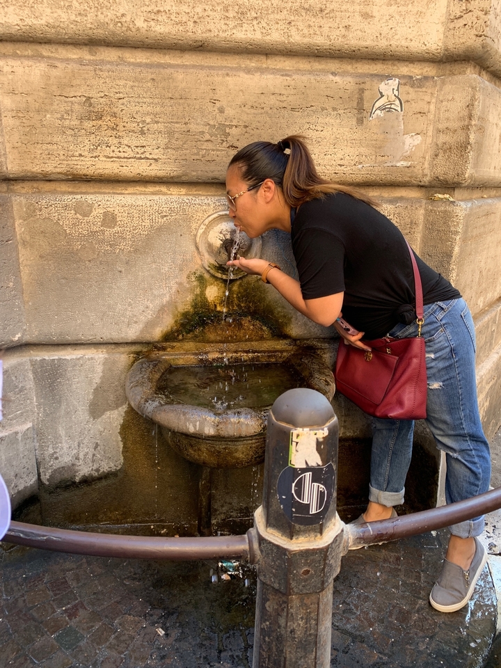 Une personne buvant à une fontaine publique historique.