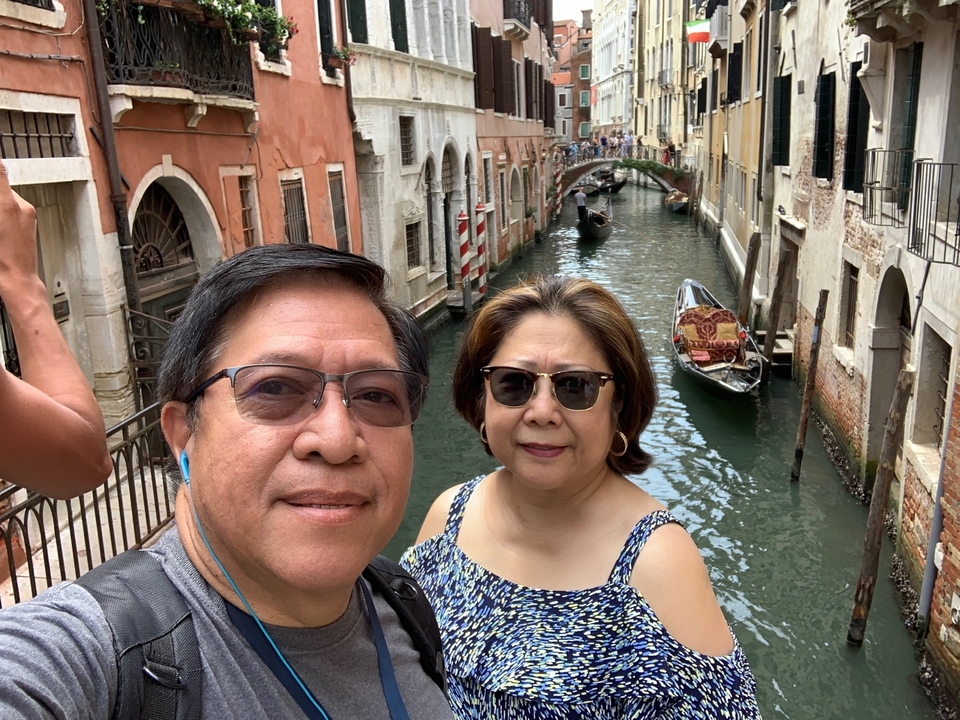 Deux personnes avec un canal et une gondole en arrière-plan.