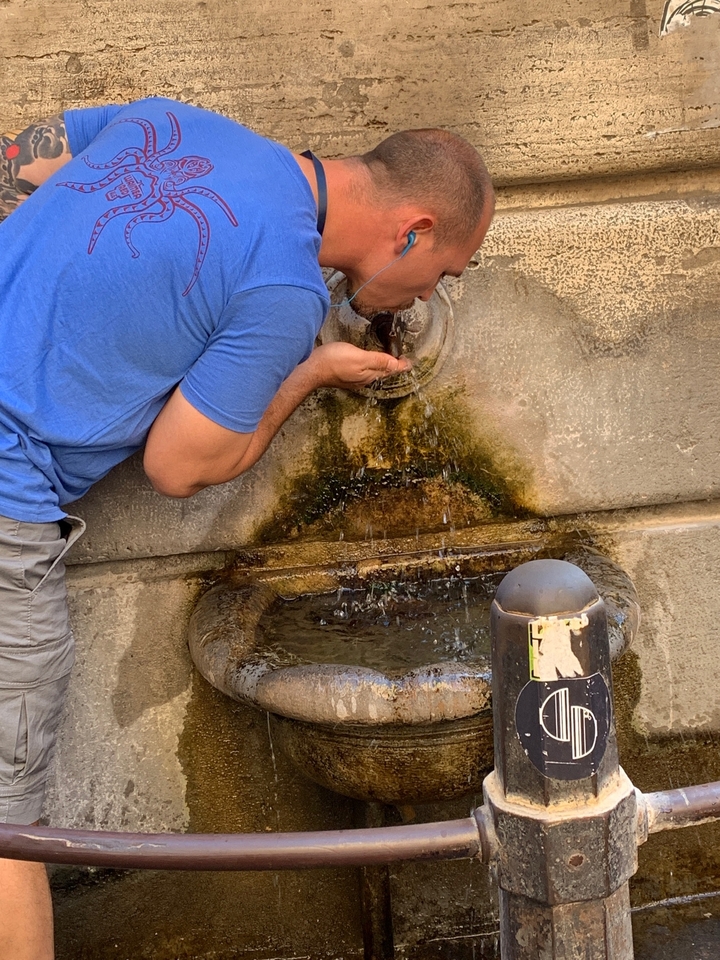 Personne buvant de l'eau d'une fontaine murale.