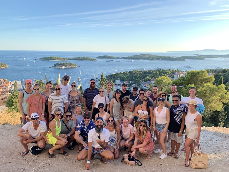 Grand groupe de personnes posant avec une vue panoramique sur des îles.