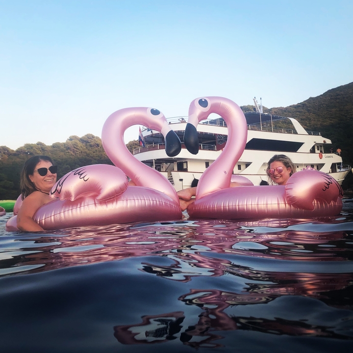 Deux femmes se détendant sur des bouées gonflables flamant rose dans l'eau.