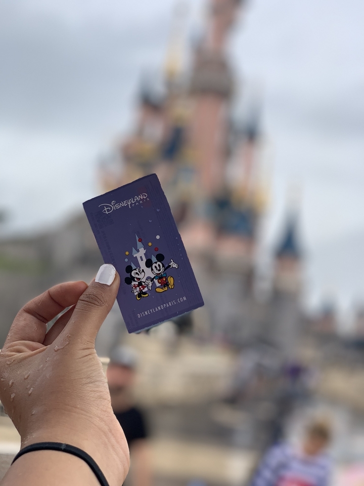Main tenant un billet de Disneyland Paris.