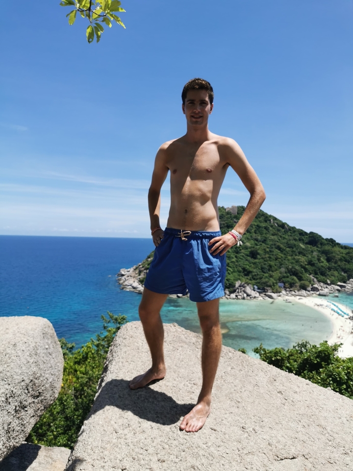 Person standing on a cliff with an ocean view.