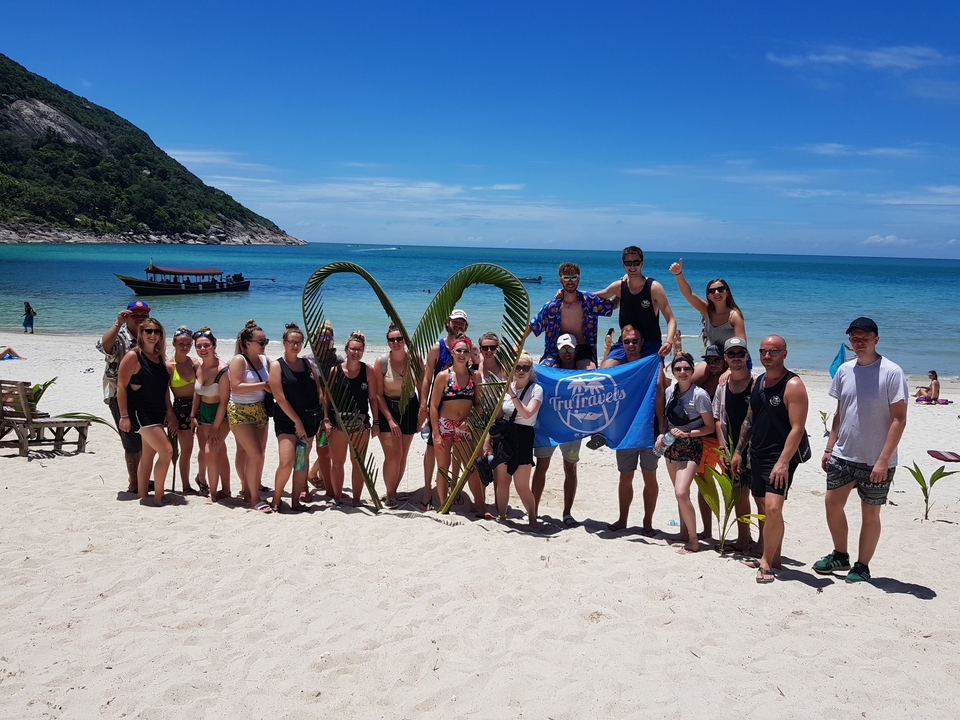 Large group on a beach, holding a blue flag.