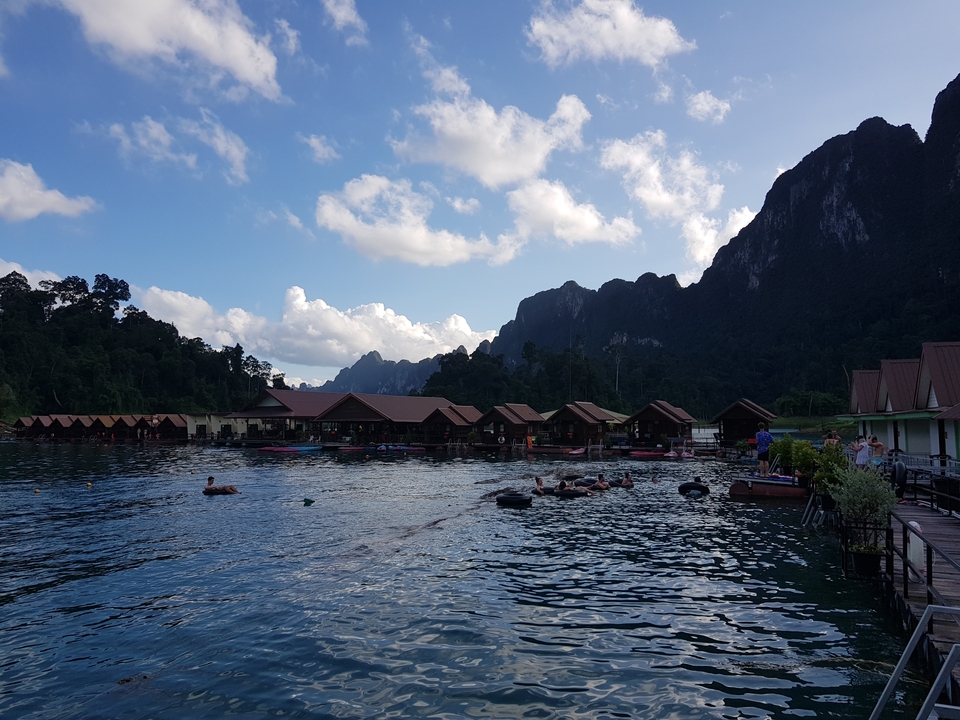 Floating cabins on a lake surrounded by mountains.