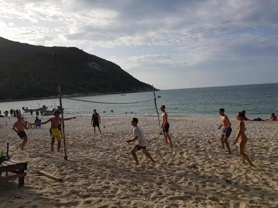 Group playing volleyball on a sandy beach.