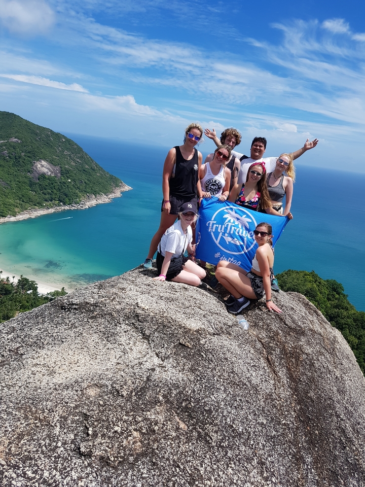 Group posing with a blue tourism flag on a hill.