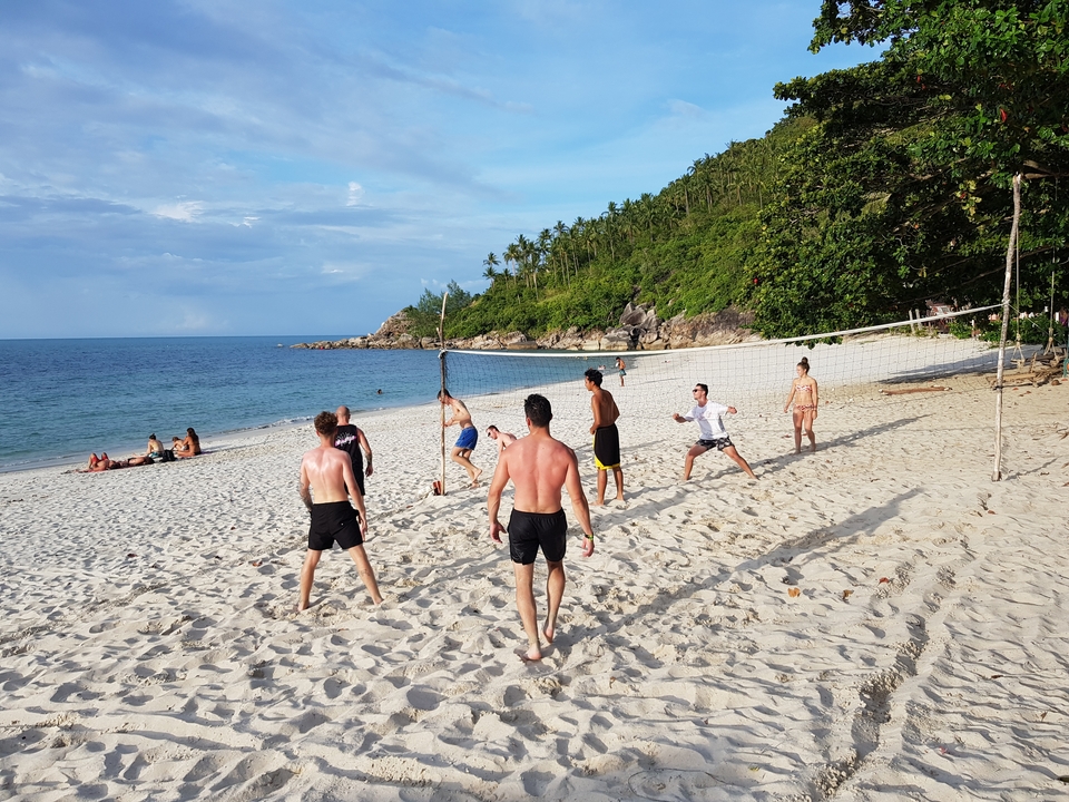 Group of people playing volleyball on the beach.