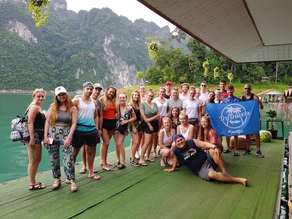Group photo on a lake dock with mountains in the background.